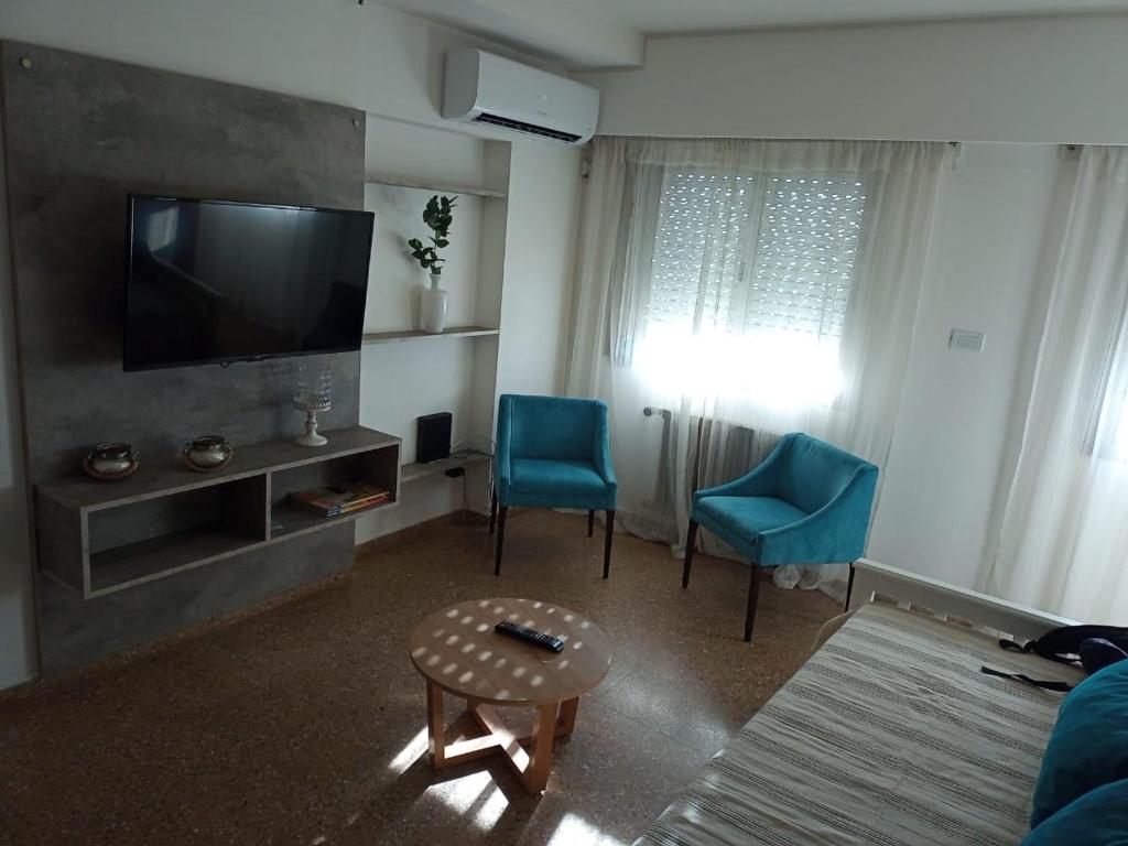 uma sala de estar com 2 cadeiras azuis e uma televisão de ecrã plano em Apart Plaza em Río Cuarto
