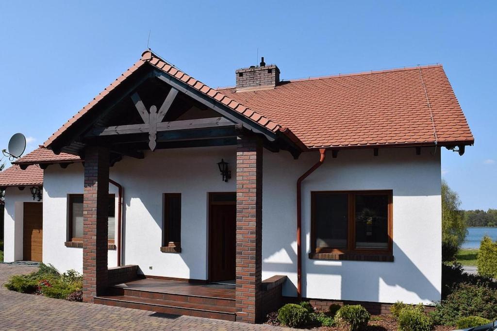 ein kleines weißes Haus mit einem roten Dach in der Unterkunft holiday home at the lake in Kiedrowice in Kiedrowice