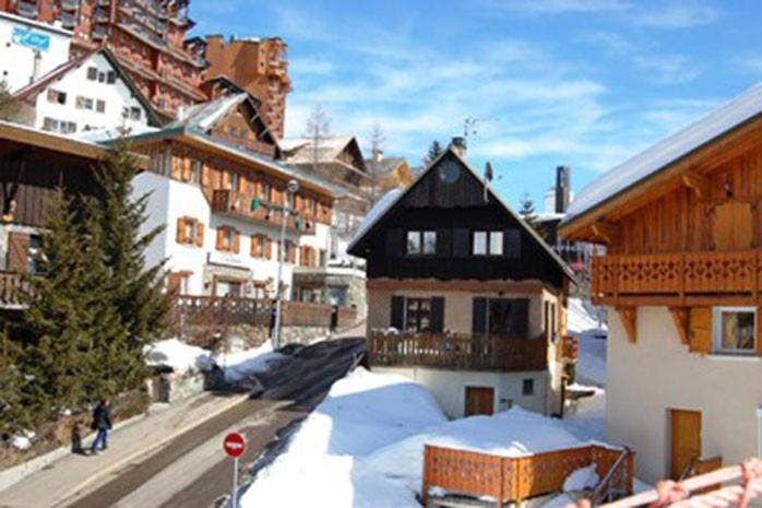 een groep gebouwen in een met sneeuw bedekte stad bij Chalet les Vieux Murs in L'Alpe-d'Huez