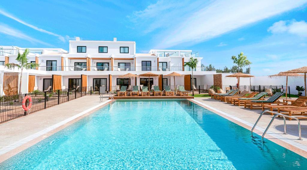 a villa with a swimming pool in front of a building at Shambhala Fuerteventura in Parque Holandes