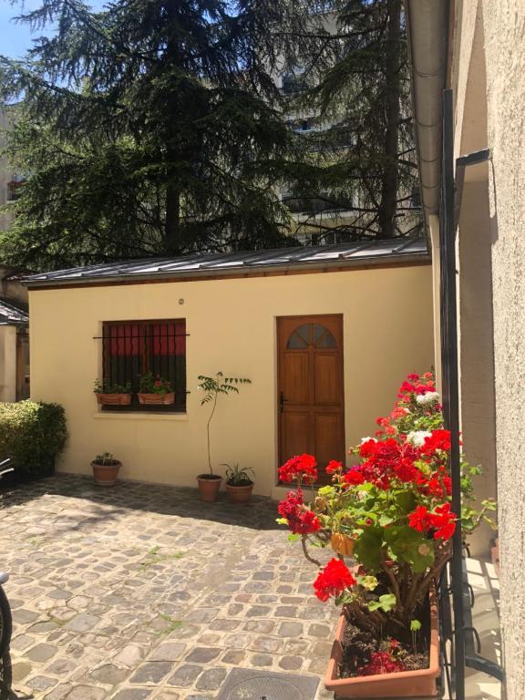 une maison avec des fleurs rouges et une fenêtre dans l'établissement Maison pour vous - TinyHouse center of Paris - logement insolite #MaCabaneAParis, à Paris