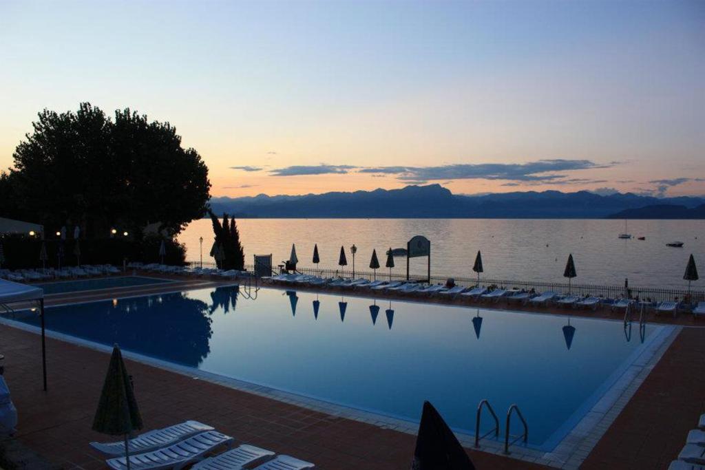 una piscina con sedie e l'oceano al tramonto di Camping Wien a Peschiera del Garda