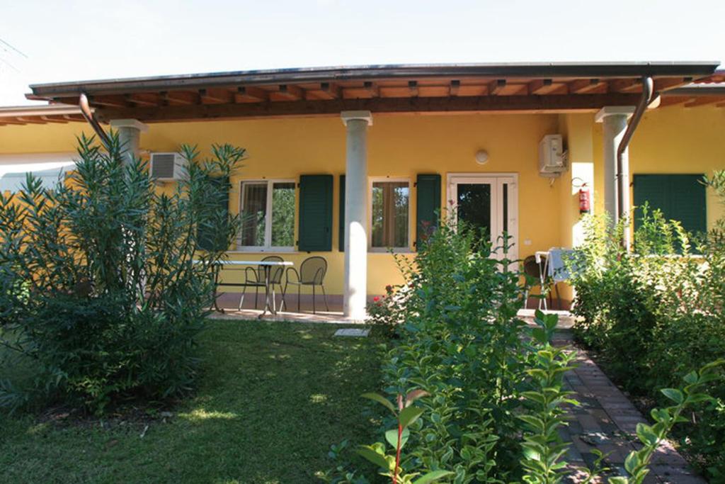 a yellow house with a table and chairs in a yard at Camping Wien in Peschiera del Garda
