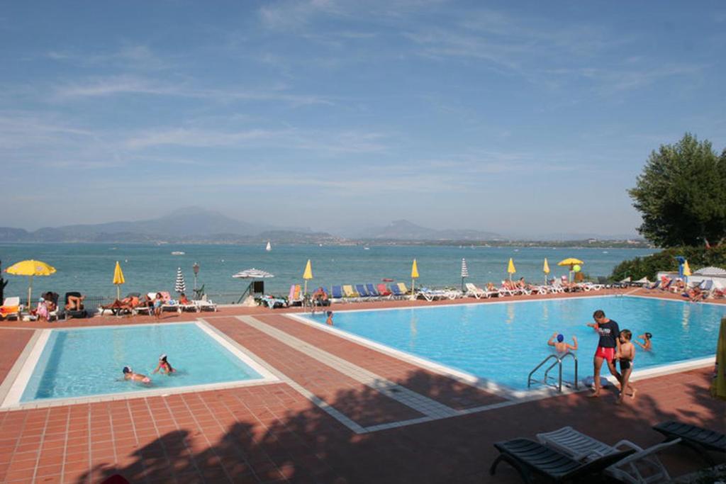 a large swimming pool with people in the water at Camping Wien in Peschiera del Garda