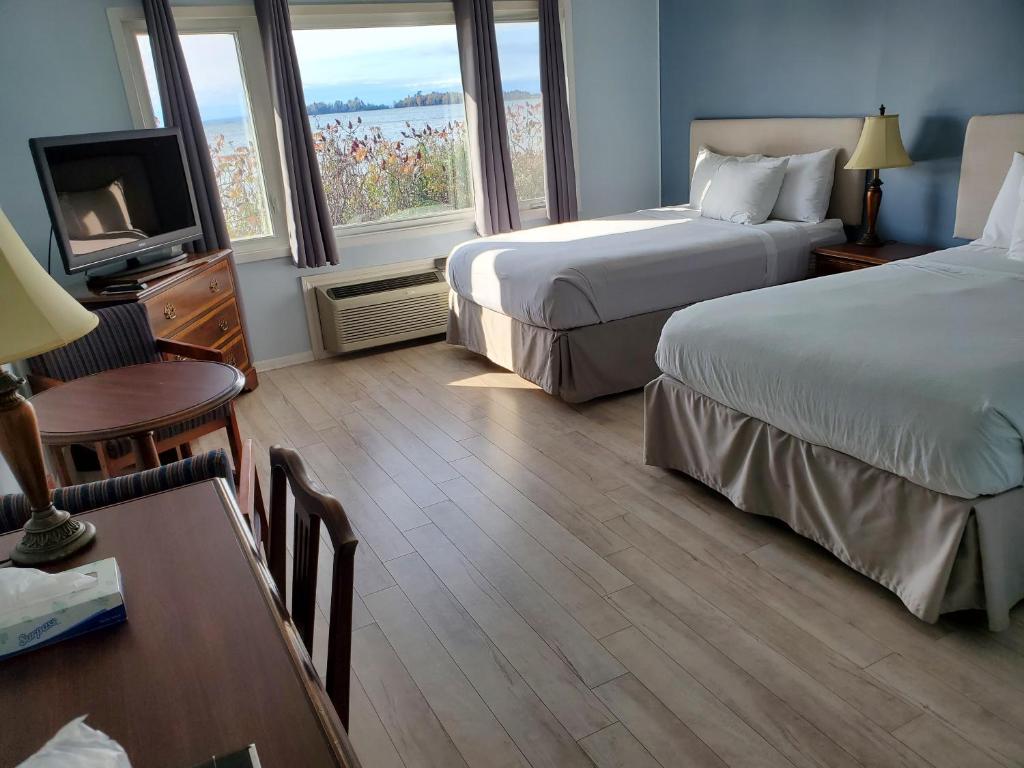 Thessalon的住宿－卡羅琳海灘汽車旅館，酒店客房设有两张床、一张桌子和电视。