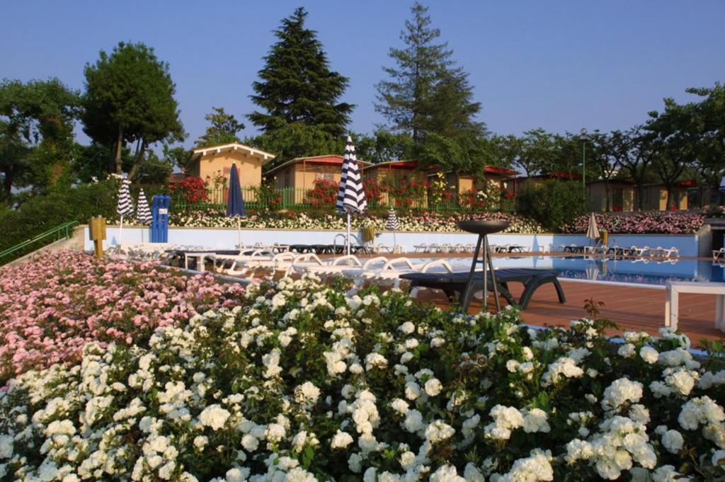 a garden with flowers in front of a building at Camping Wien in Peschiera del Garda