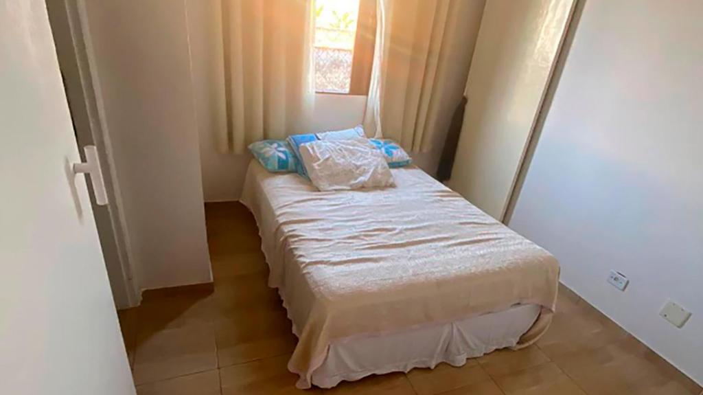 a small bedroom with a bed with pillows on it at Novidade - Apto a 500 metros da praia da Enseada in Guarujá