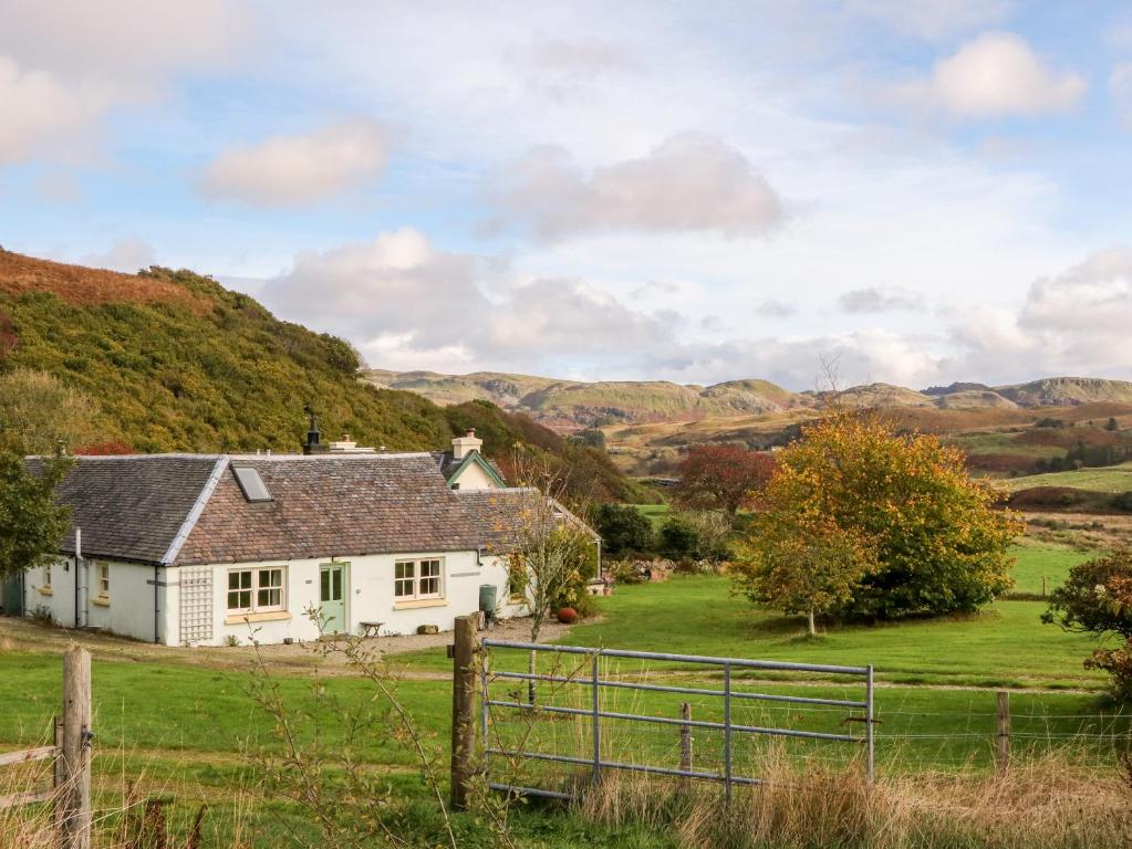 a white house in a field with hills in the background at Mullach in Lunga