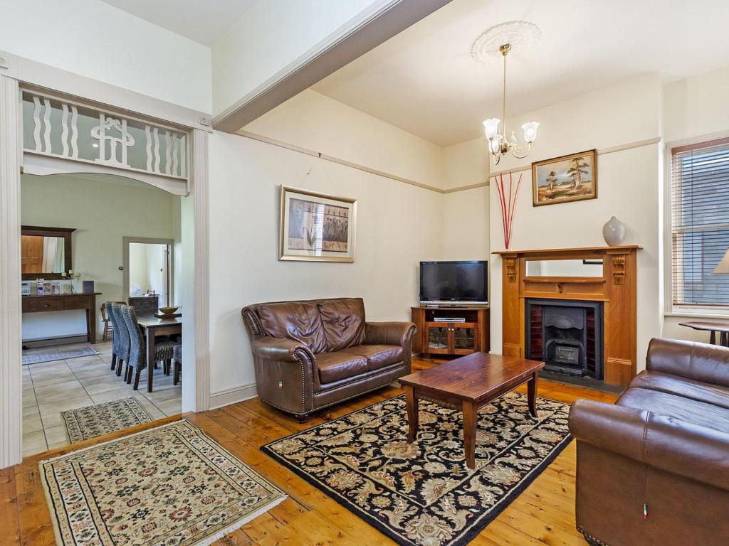 a living room with leather furniture and a fireplace at Fairholme Townhouse in Warrnambool