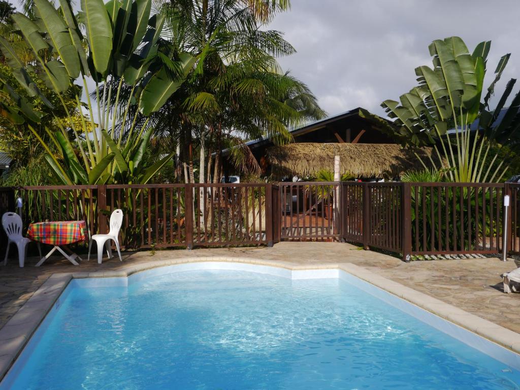 a swimming pool in a yard with a fence at Hotel La Marmotte** in Matoury