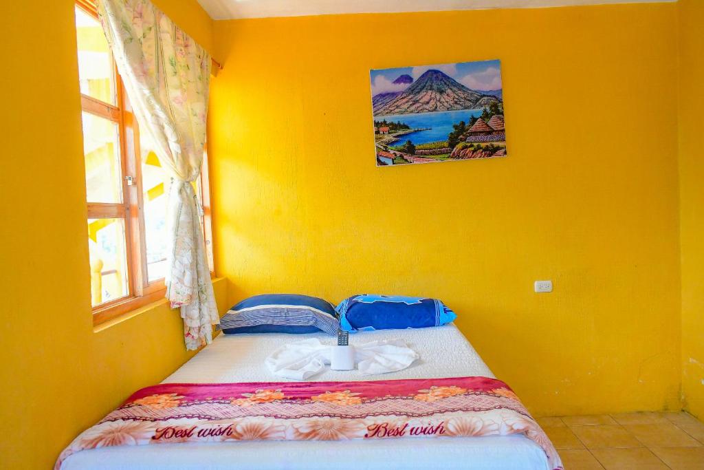 a yellow bedroom with a bed in a yellow wall at Hotel Villa del Lago in San Pedro La Laguna
