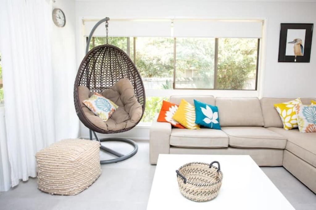 sala de estar con sillón colgante y sofá en Kookaburras at South Golden - NEW modern beach house - Quick walk to pristine beach en South Golden Beach