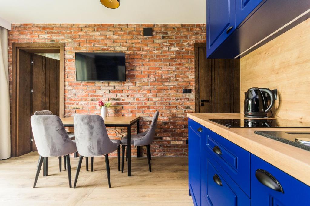 斯蒂格纳Apartamenty Gajówka- rowery, plac zabaw, sauna, jacuzzi的厨房配有蓝色橱柜和桌子及椅子