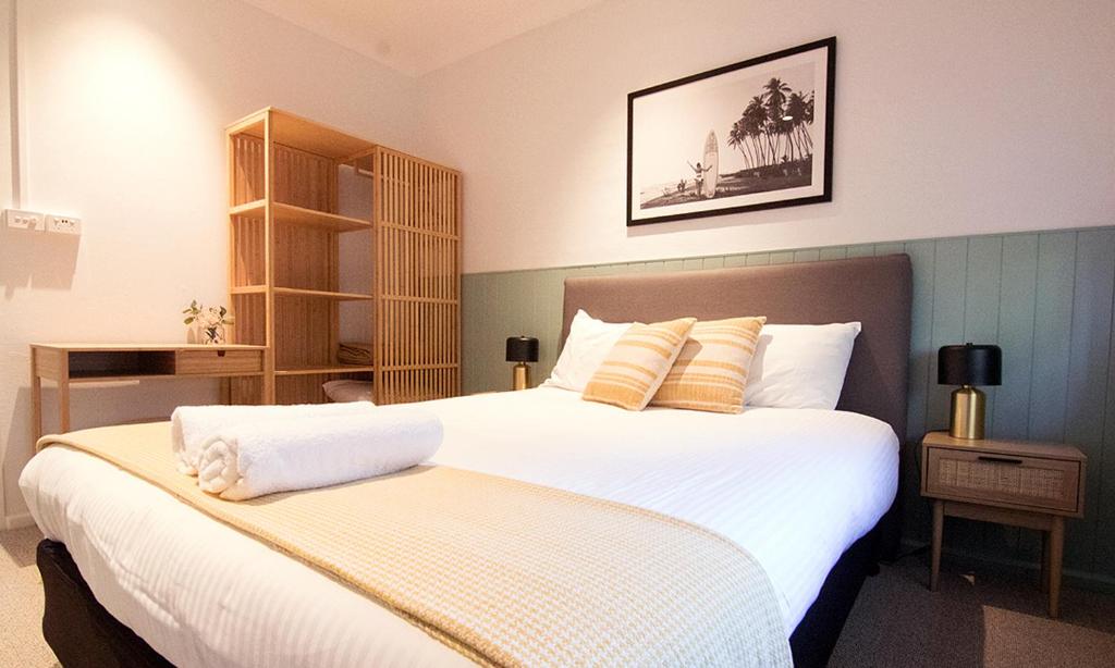 1 dormitorio con 2 camas con sábanas blancas y almohadas amarillas en The Carmel Yamba en Yamba