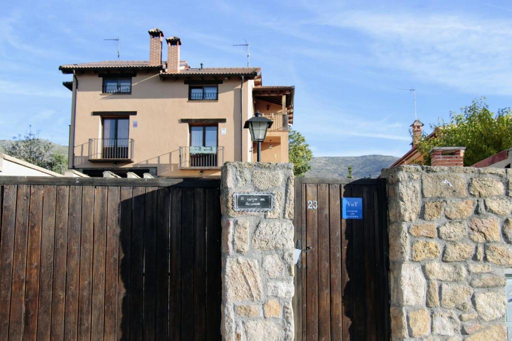 una casa detrás de una valla de madera con una puerta en El Camino del Arcipreste, en Otero de Herreros