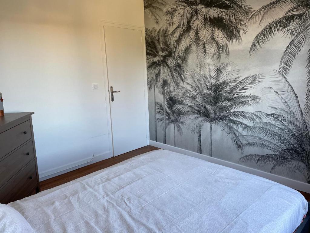 a bedroom with a bed with a mural of palm trees at Maison chaleureuse in Villeneuve-sur-Lot