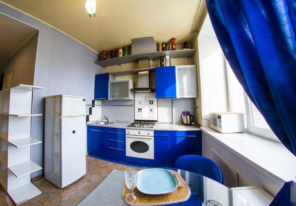 オムスクにあるRENT-сервис Apartment on Maslennikova 9のキッチン(青いキャビネット、白い冷蔵庫付)