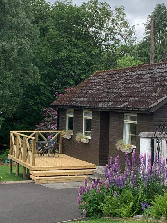 una casa con una terraza de madera con un banco. en Creity Hall Chalet, en Stirling