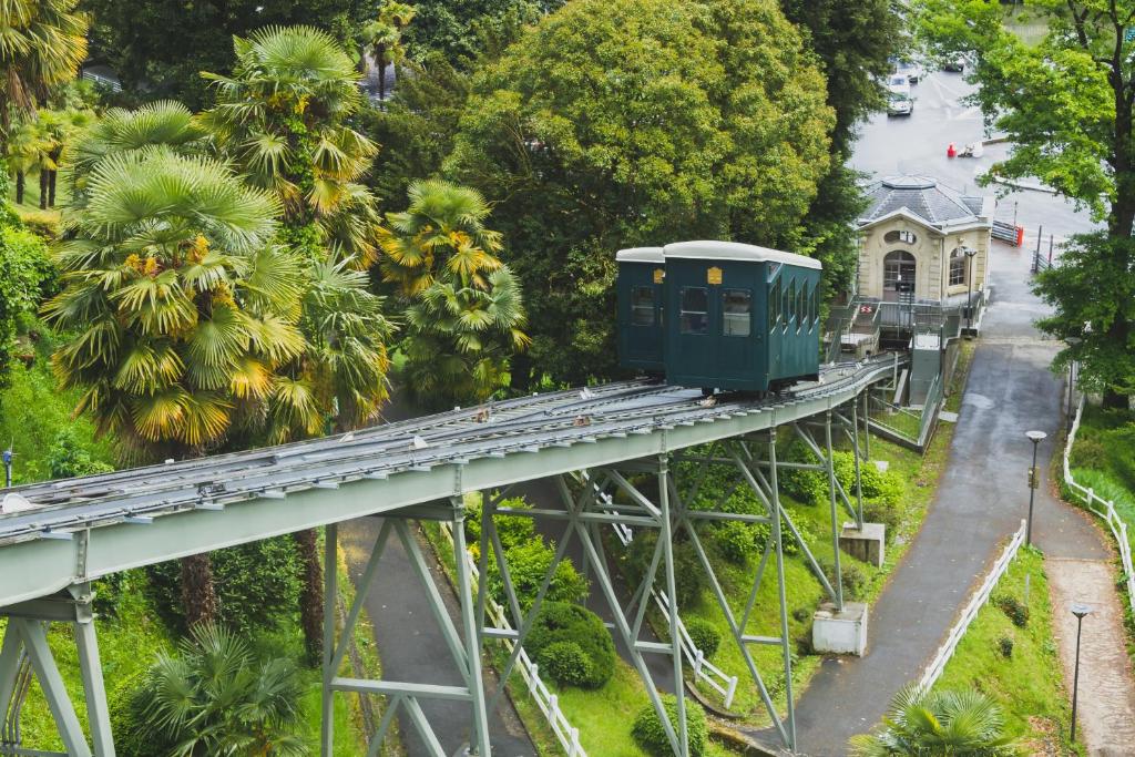 a green train on a bridge over a street at ONLOC - St Exupéry -Magnifique appart au calme avec chambre - parking in Pau