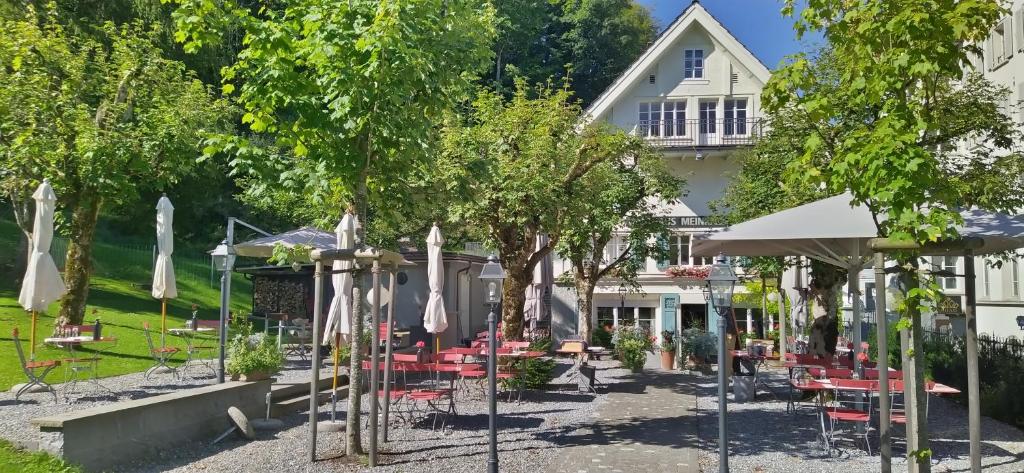 une terrasse avec des parasols, des tables et des chaises en face d'une maison dans l'établissement Gasthaus Meinradsberg, à Einsiedeln