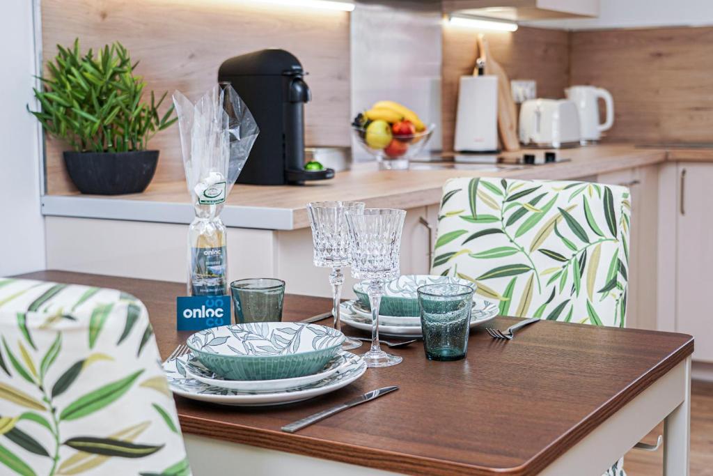 a wooden table with plates and glasses on it in a kitchen at ONLOC - St Exupéry -Magnifique appart au calme avec chambre - parking in Pau