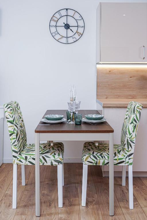 a dining room table with two chairs and a clock at ONLOC - St Exupéry -Magnifique appart au calme avec chambre - parking in Pau