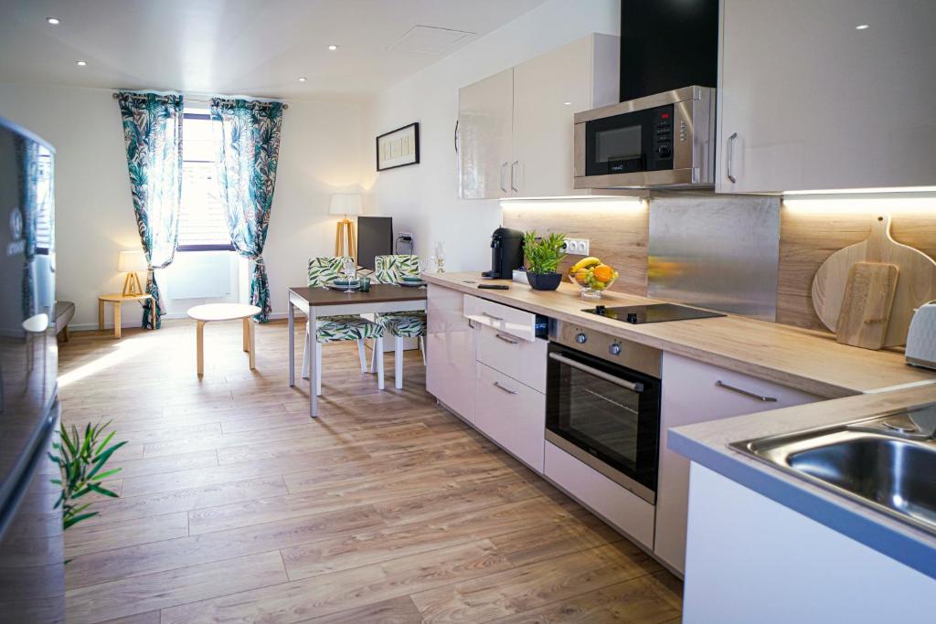 a kitchen with white cabinets and a counter top at ONLOC - St Exupéry -Magnifique appart au calme avec chambre - parking in Pau