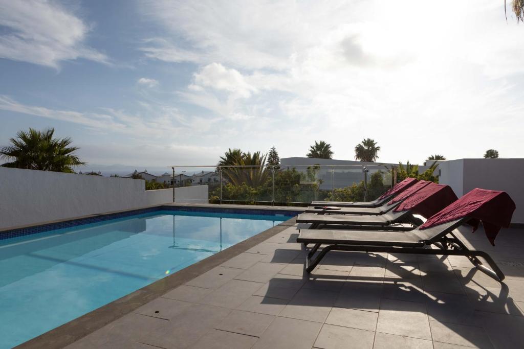 a pair of lounge chairs sitting next to a swimming pool at Hoopoe Villas Lanzarote in Playa Blanca