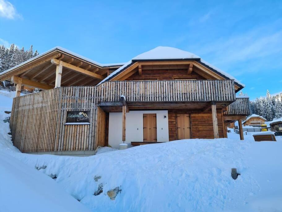 una cabaña de madera con nieve delante en Edelweiss Chalet, en Oberwölz Stadt