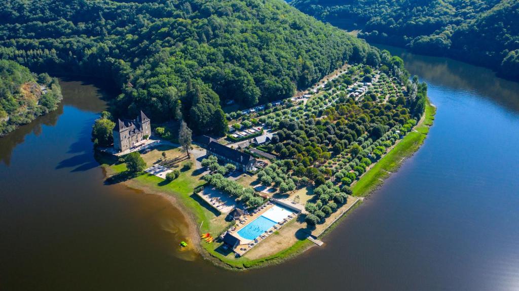 een eiland in het water met een huis en een zwembad bij Camping Le château du gibanel in Saint-Martial-Entraygues