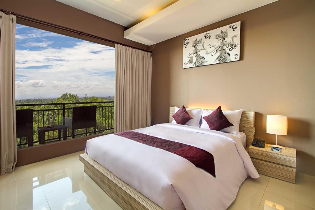 1 dormitorio con cama grande y ventana grande en ABISHA Resort Jimbaran, en Jimbaran