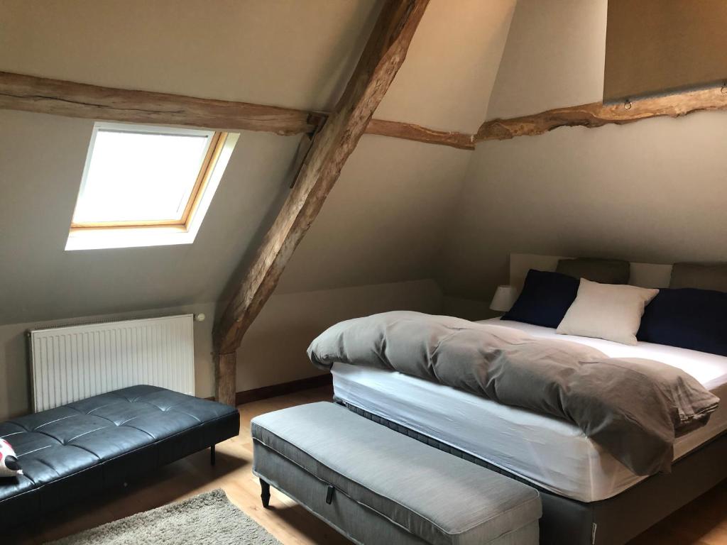 ein Schlafzimmer mit einem Bett und einer Bank in einem Zimmer in der Unterkunft Le Domaine des Volets bleus in Beuzeville
