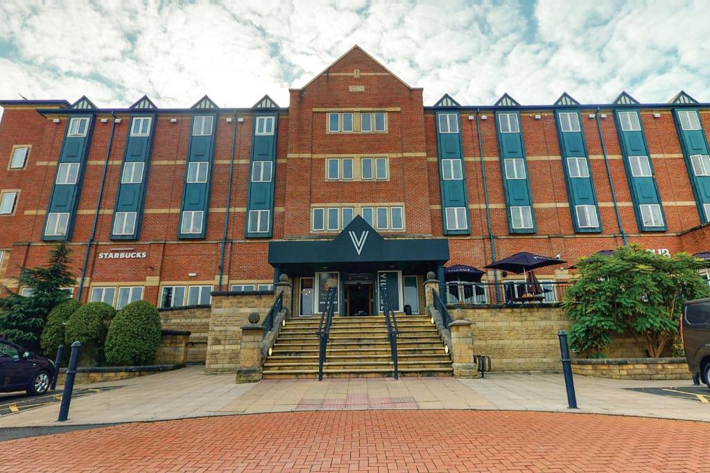 un grande edificio in mattoni rossi con una scala di fronte di Village Hotel Birmingham Walsall a Walsall