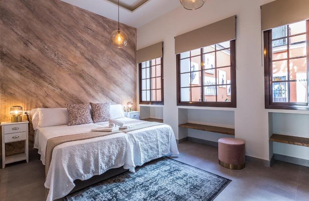 a bedroom with a large bed and two windows at Los Corceles Casa Palacio in Jerez de la Frontera