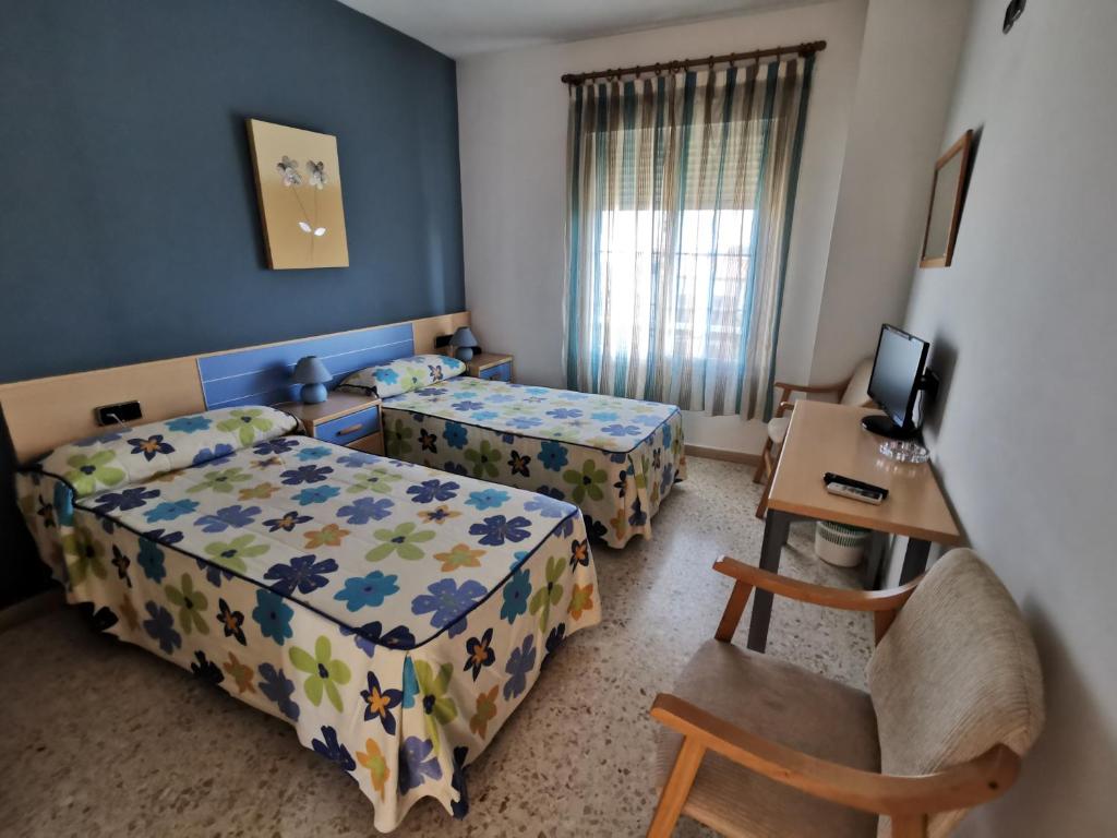 Talavera la Real的住宿－塔拉韋拉旅館，一间卧室配有两张床、一张桌子和一张桌子
