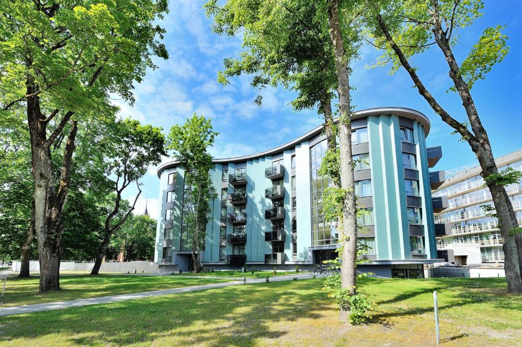 een gebouw met bomen ervoor bij Valensia Apartment in Druskininkai