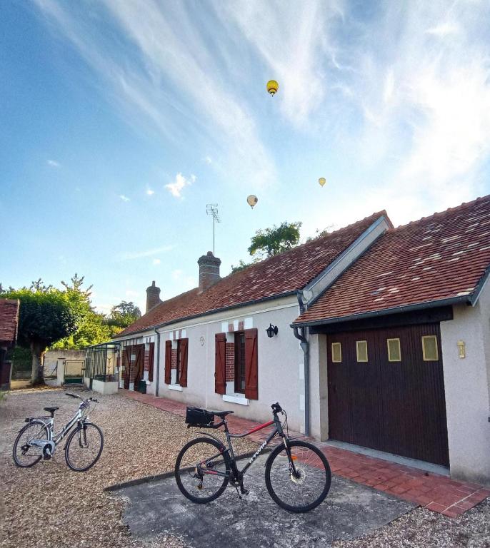 deux vélos garés devant une maison avec des ballons dans le ciel dans l'établissement la longère de l allée du château de Cheverny, à Cheverny