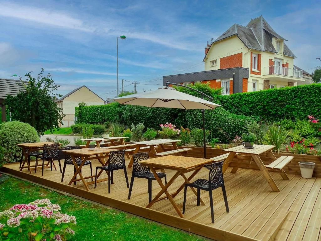 eine Holzterrasse mit Tischen, Stühlen und einem Sonnenschirm in der Unterkunft Hotel Ibis Budget Fecamp in Fécamp