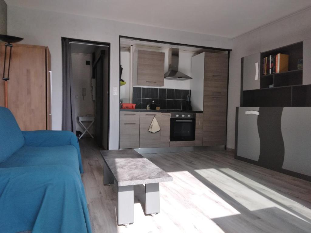 un salon avec un canapé bleu et une cuisine dans l'établissement Résidence St Hélion, à Sète