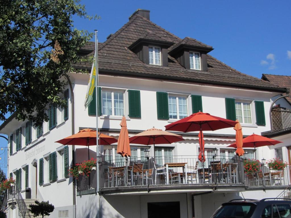 un edificio con mesas y sombrillas delante en Landgasthof Schwanen, en Felben
