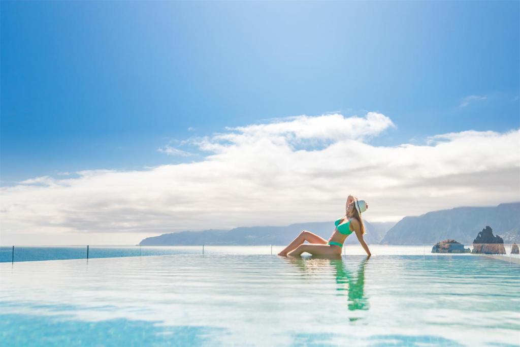 a woman sitting in the water in a infinity pool at Aqua Natura Bay in Porto Moniz