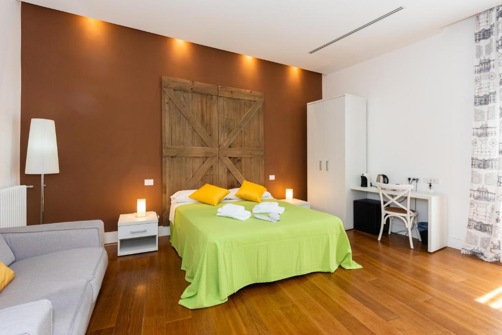 um quarto com uma cama com um cobertor verde e almofadas amarelas em IHH Suites Rome em Roma