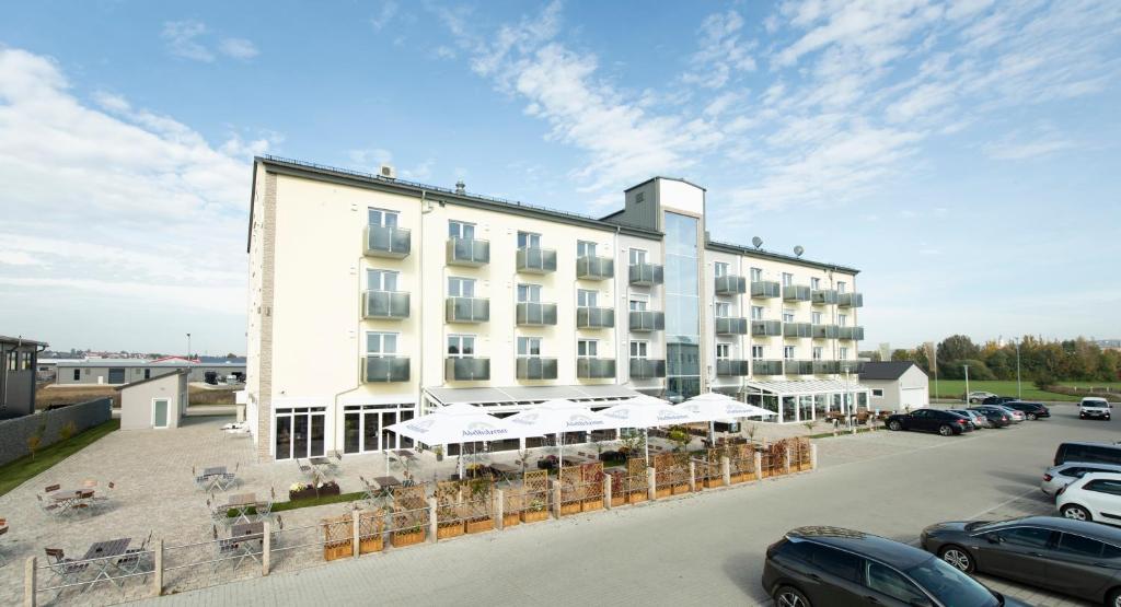 a large white building with cars parked in a parking lot at Stadthotel Donauwörth in Donauwörth