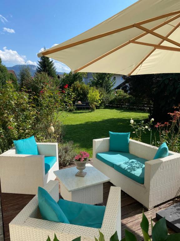 un patio con 2 sillas, una mesa y una sombrilla en Charmantes Garten-Apartment: Erholung im Chiemgau, en Unterwossen