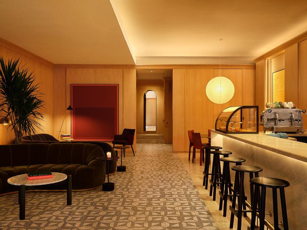 a lobby with a couch and a bar with stools at The Moore in New York