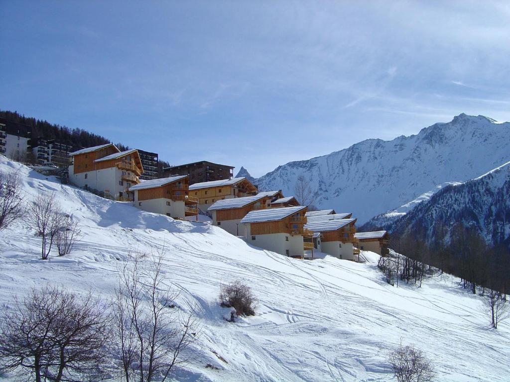 un grupo de edificios en una montaña cubierta de nieve en Goélia Les Chalets des Deux Domaines en Peisey-Nancroix