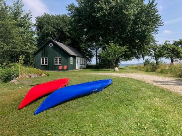 deux bateaux assis sur l'herbe devant une maison dans l'établissement Strynø Living, à Rudkøbing