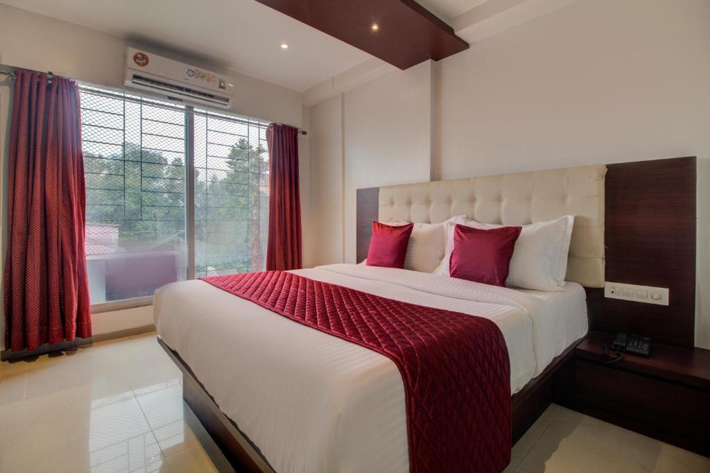 a bedroom with a large white bed with red pillows at Hotel Malad Inn opposite Malad Railway Station in Mumbai