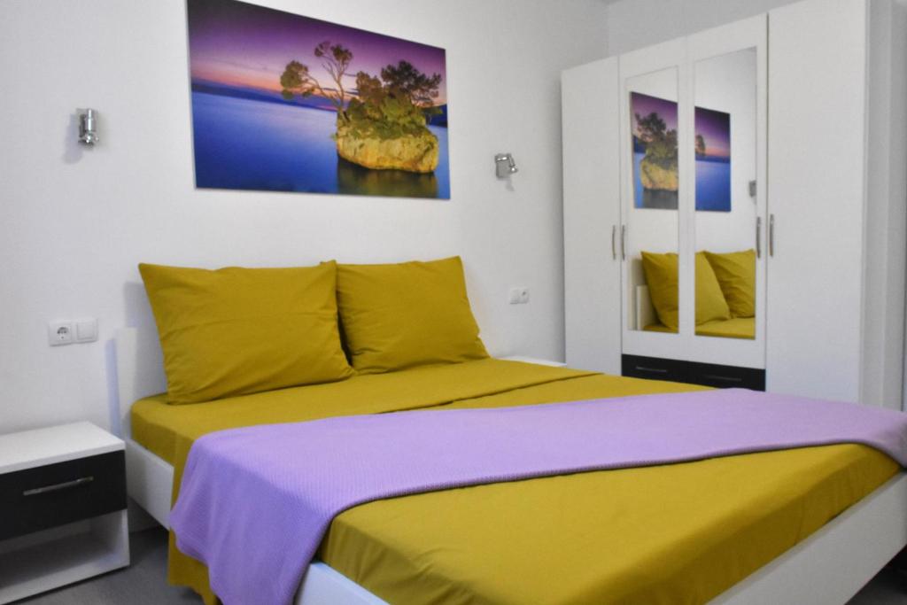 a bedroom with a yellow bed and a painting on the wall at Apartment Meryl in Mravince