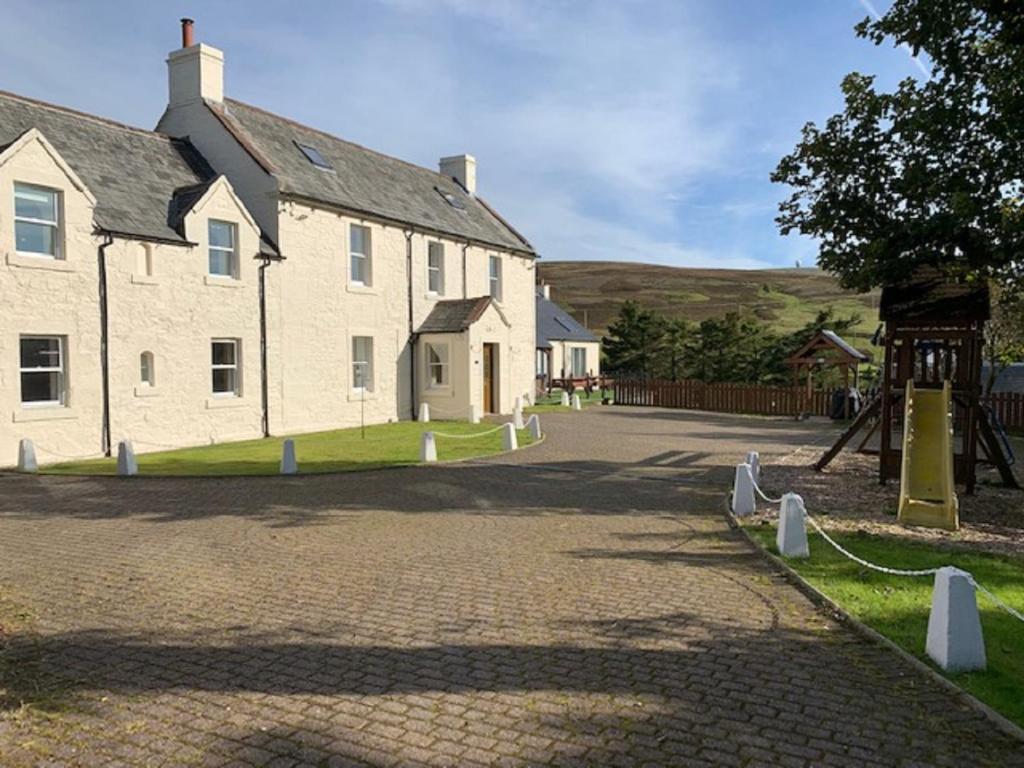 a large white building with a playground in front of it at Belton House Holiday Home in Wanlockhead